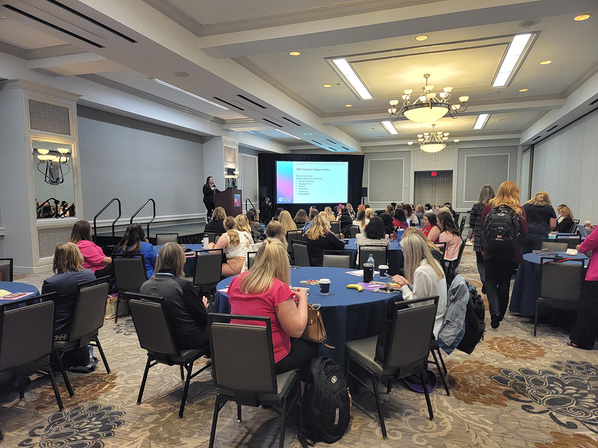 Recap: 2024 SBN Women’s Leadership Forum Empowers Females in Automotive - Women seated at tables watching presentation by a speaker