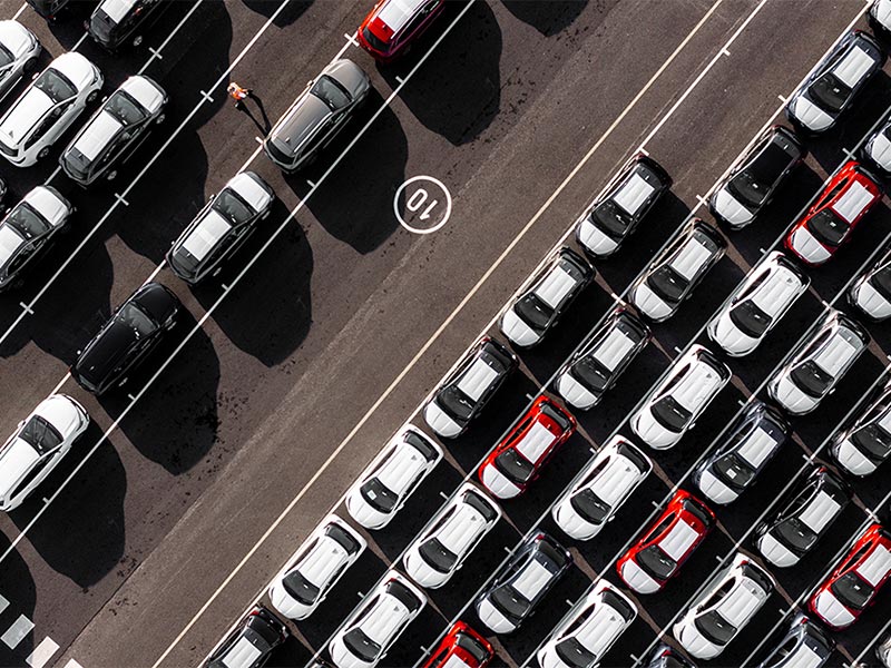 Overhead view of cars lined up in a port area ready for shipment