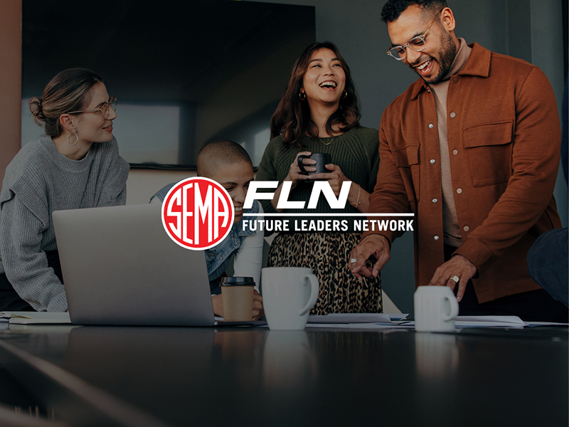 Smiling and laughing people gathered around a table with laptop and coffee
