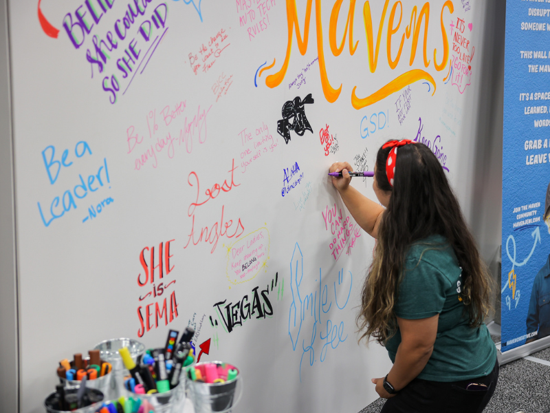 Woman signing a whiteboard at the SBN Booth