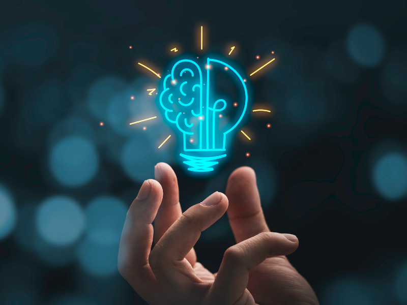 Hand holding imaginary illuminated lightbulb and brain graphic. 