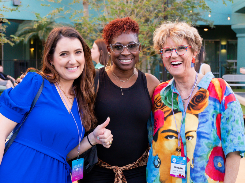 Three women smiling for the camera. One is giving thumbs up