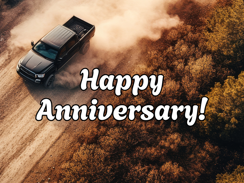 Aerial view of a truck kicking up dirt while driving down a dirt road with Happy Anniversary overlaid.