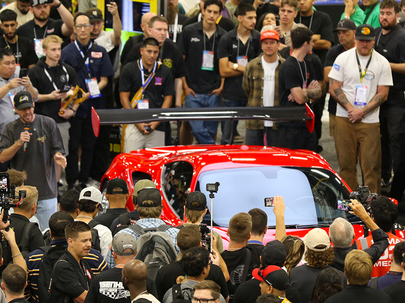 An image of a vehicle unveiling in a booth at the SEMA Show.