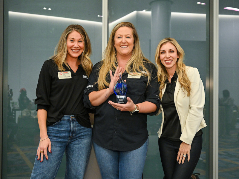 Kirstin Backes holding her award for #SheIsSEMA Woman of the Year.