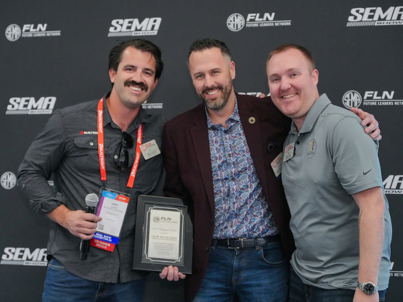Men smiling in front of a step and repeat