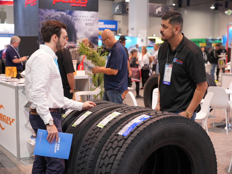 Exhibitor and Attendee speak over a display of tires