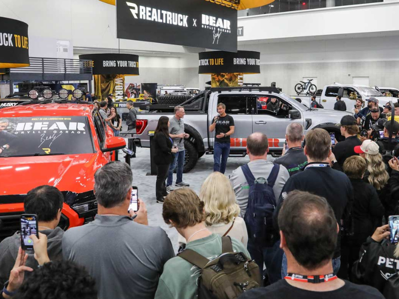People look on as an exhibitor speaks at their booth at the SEMA Show