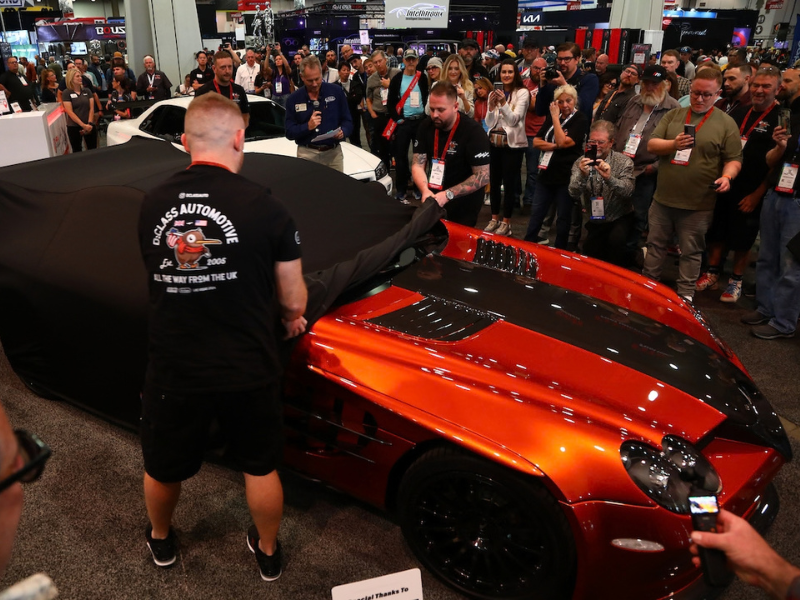 Crowd gather around a car unveiling at the SEMA Show. 