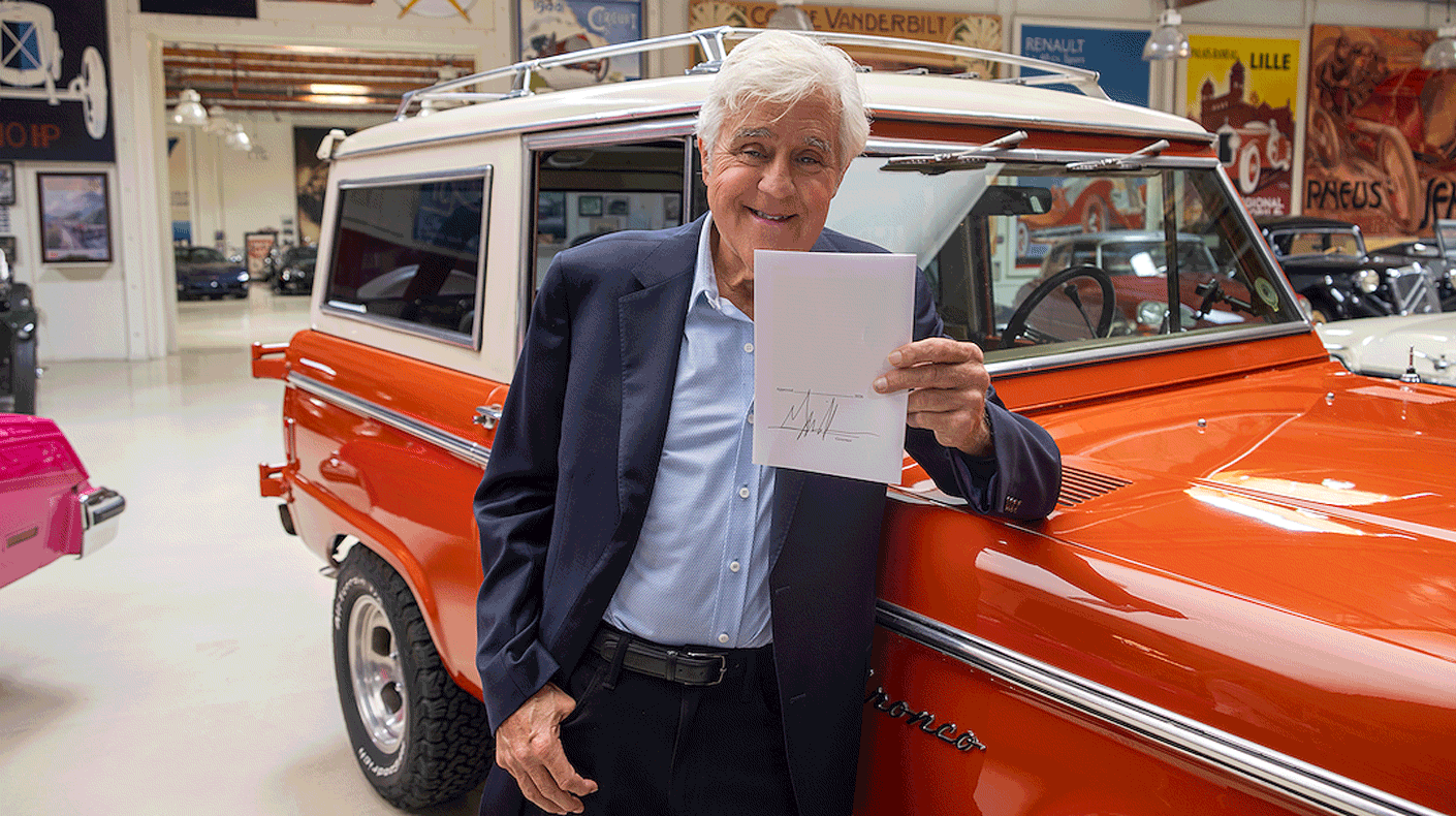 Jay Leno holding a bill signed by Gavin Newsom.