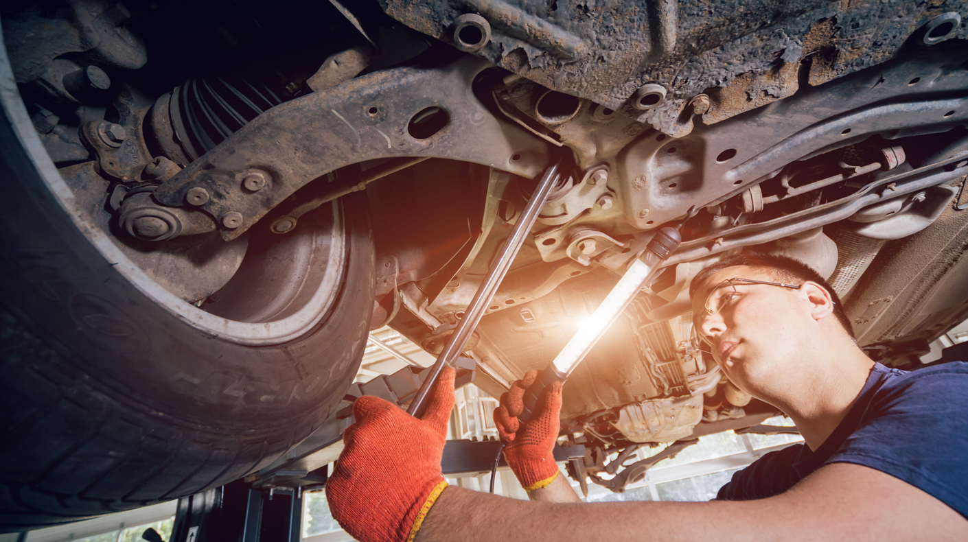 An image of a car mechanic looking at the suspension.
