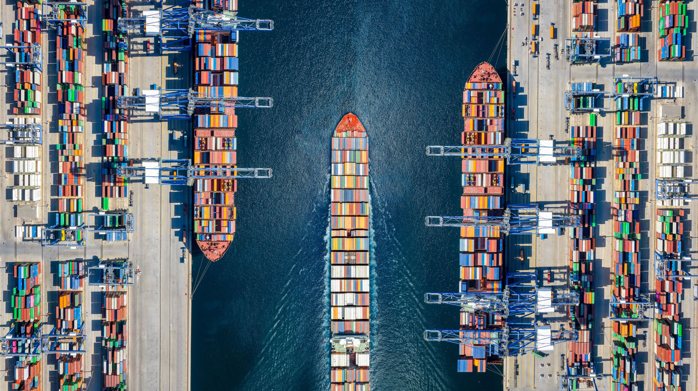 Aerial top down view of a large container cargo ship terminal with loading activity and vessel traffic.