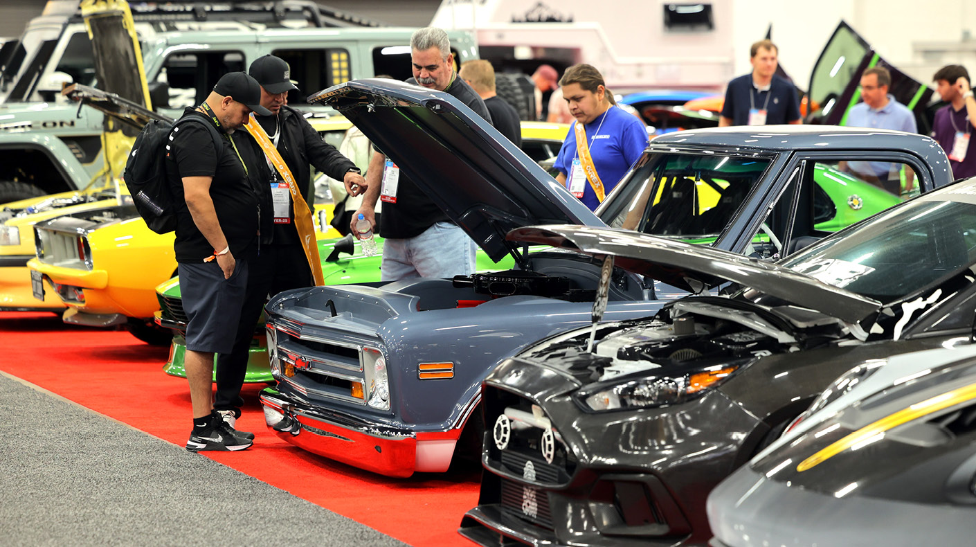An image of attendees looking at open hoods at the SEMA Show.