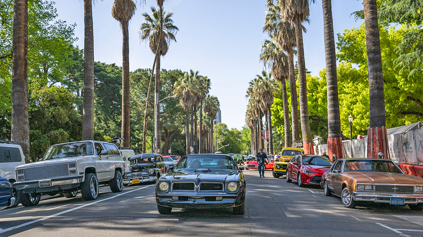 Classic cars driving down a California street.