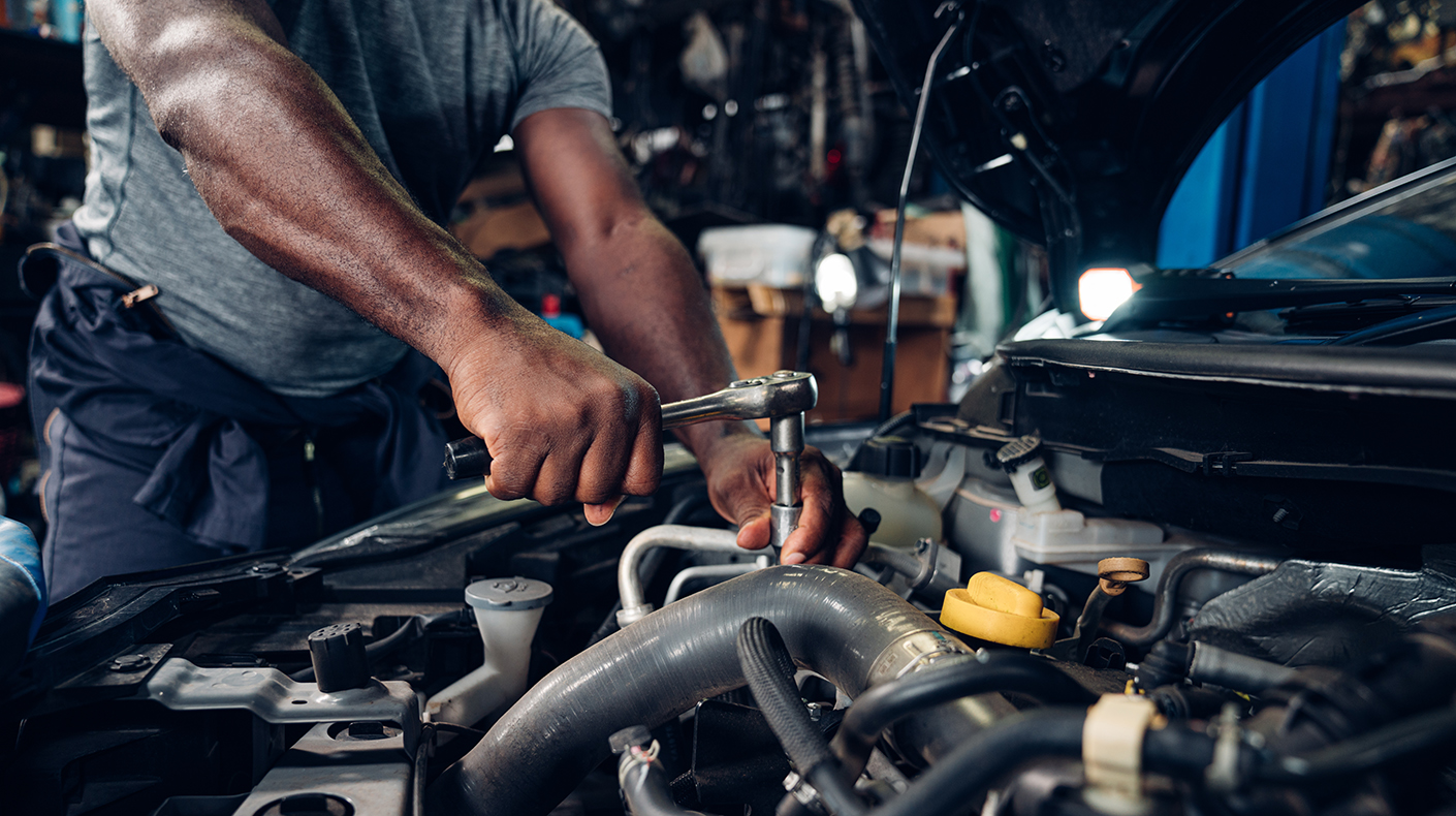 A mechanic working under the hood of a car.