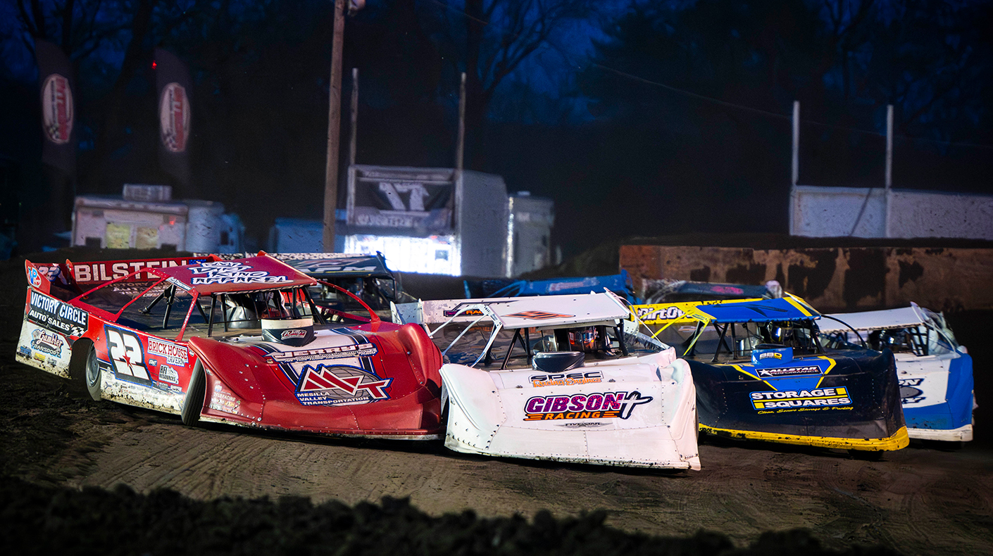Late model dirt cars racing on a dirt track.