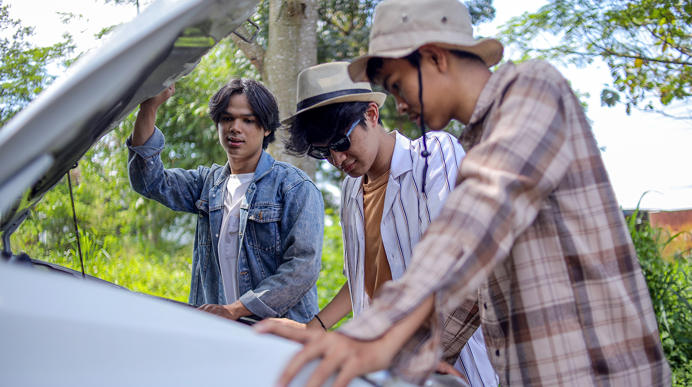 Gen Z age guys looking under the hood of a car.
